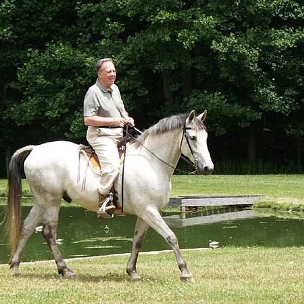 Bill Neuberg riding a grey gaited horse at Nearaway Farm