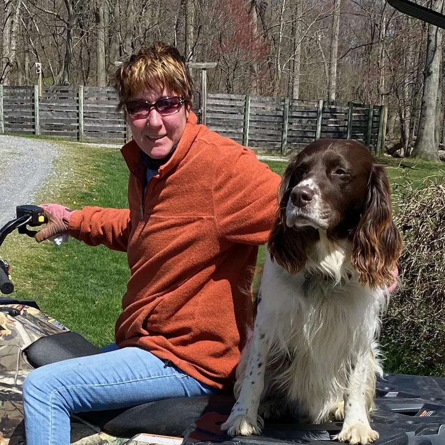 Dawn Adams on a quad by the barn with her spaniel sitting beside her