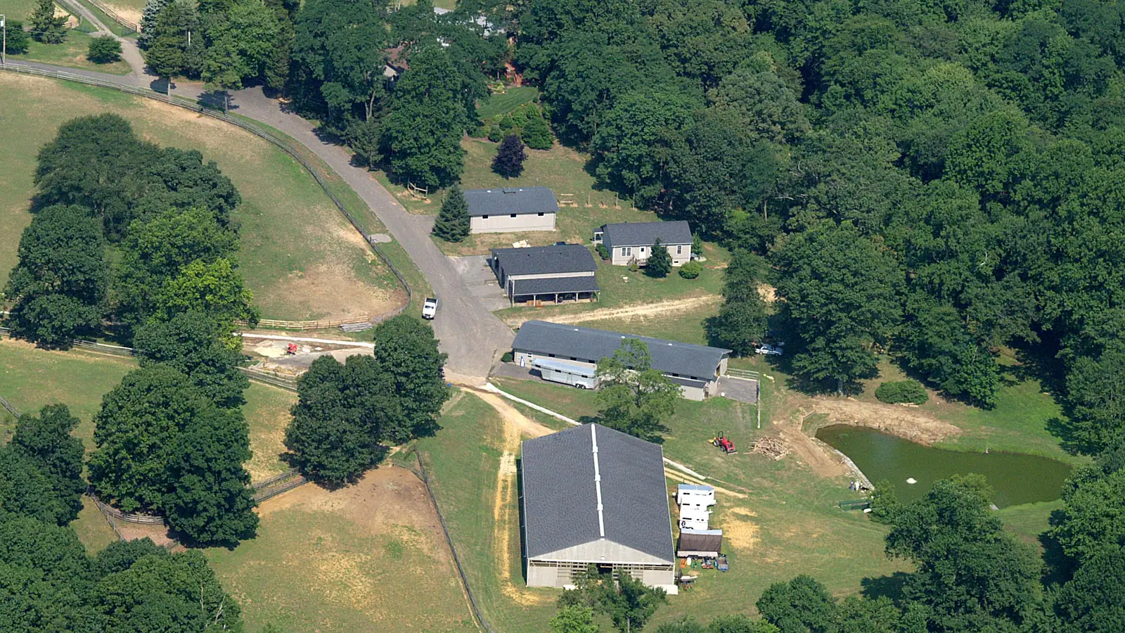 Nearaway Farm from the air, showing the barns, paddocks, pond, and surrounding woodland