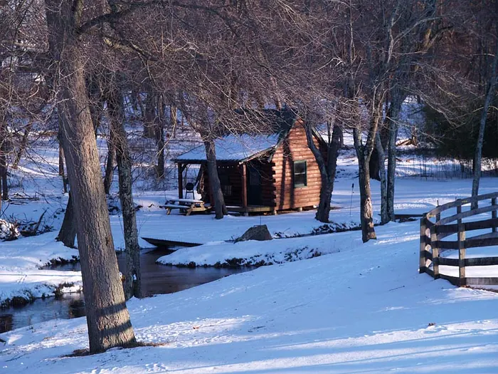 The log cabin and creek on the property under snow